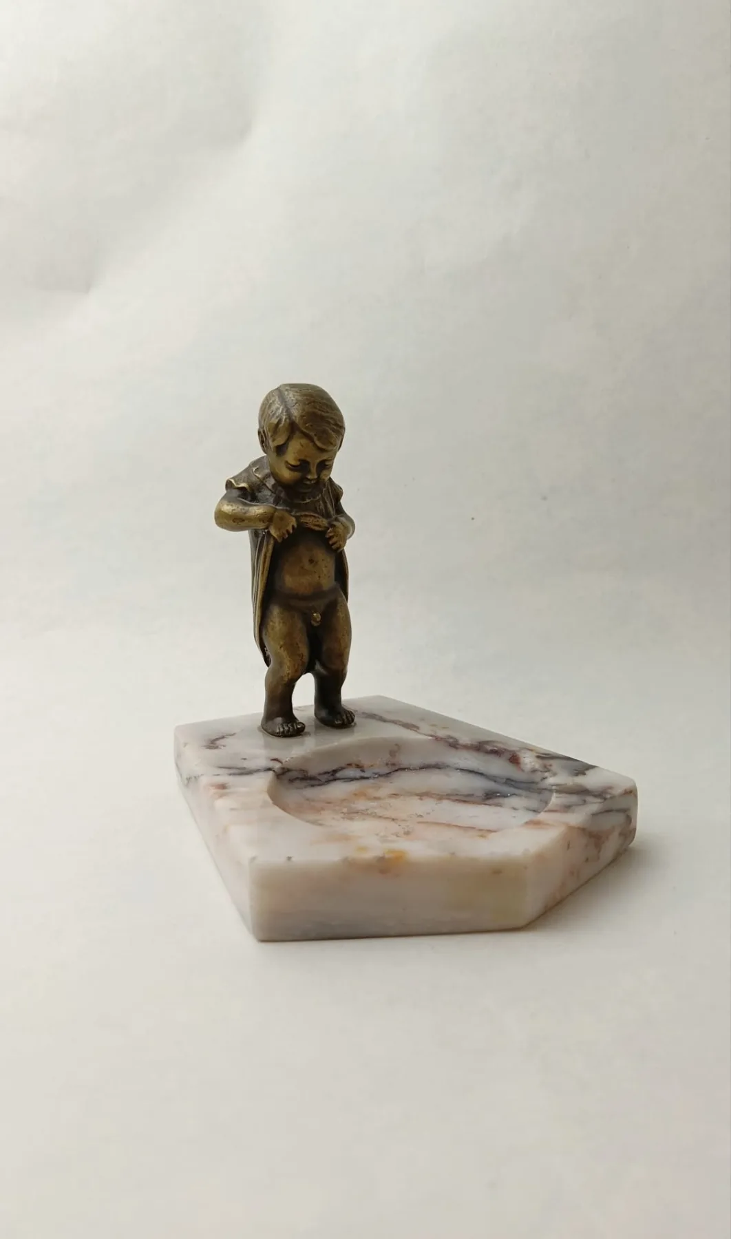 Bronzová figurka čůrajícího chlapečka na mramorovém podstavci